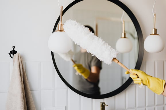 person-dusting-bathroom-light-fixtures