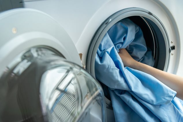 person-putting-blue-sheet-in-dryer